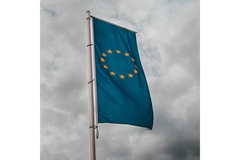 EU flag against grey sky.