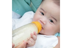 Image Baby drink formula from bottle.