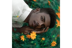 Man with septum piercing surrounded by foliage and flowers