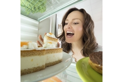 Image Woman eating slice a cake from a fridge.
