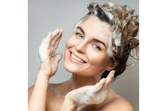 A woman washing her hair with shampoo.