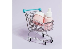 Image A miniature shopping cart filled with skin care products.