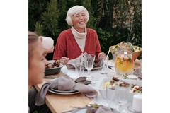 Image Old woman smiling at a table with food.