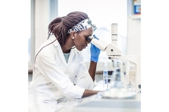 Image A woman looking into a microscope.