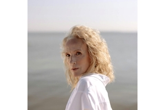 Image Old woman in white shirt standing near a body of water.