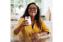 Image Woman holding up a glass of milk.