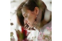 Image Side profile of woman looking to the left behind flowers.