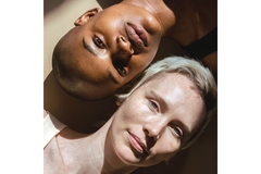 A black and white woman lying down on opposite sides with the sun on their faces.
