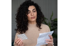 Woman checks paper before taking supplements.