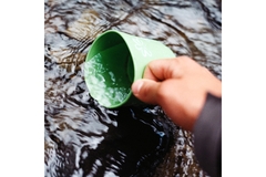 Person Scooping Water Using Green Cup