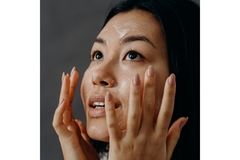 A woman putting her hands up to her face while wearing a face mask.