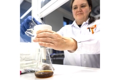 A female scientist in the lab pouring lab grown coffee into a flask.