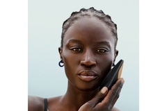 Woman holding a beauty device to her cheek.