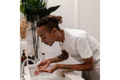 Image A man washing his face in the sink.