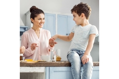 Woman feeding a child sitting on a kitchen island.