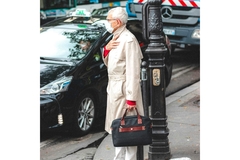 An older man prepares to cross the street but appears to have trouble breathing and is wearing a mask.