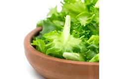 Image A bowel of lettuce is placed on a white table.