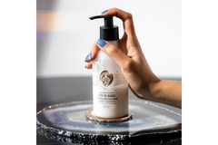 A hand on the pump of a lotion from The Body Shop.