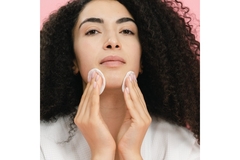 Image A woman wiping her face with skin pads