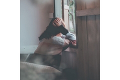 Image Sad woman sits by the window.