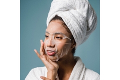 Image A woman wearing a face mask with her hair in a towel.