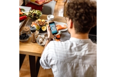 Man checking his phone while at a table with healthy foods.