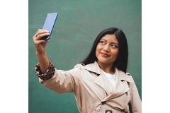 A woman wearing a trench coat while taking a selfie.