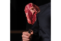 A man holding a steak cut on a butcher's knife.
