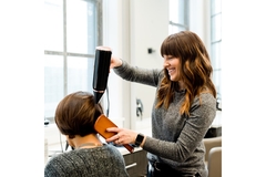 Image A hair stylist blow drying a clients hair.