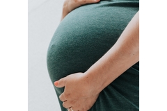 Image A married pregnant woman is holding her belly.