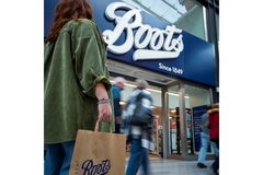 Image A woman holding a Boots bag in front of a Boots store.