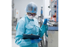 Image Food technician in a factory, in food safety clothing, checking a clipboard.