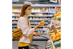 Image woman picking out orange at a supermarket