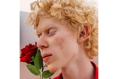 Image A man holding a rose with his eyes closed.