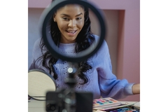 Image Smiling black woman talking to smartphone during live broadcast