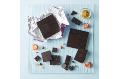Image The chocolate bar is displayed on a blue table with red strawberries.