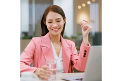 Businesswoman behind her computer, taking a supplement.