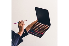 Image Holding up a makeup palate and putting a brush into it.