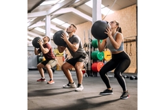 People in a fitness class, squatting with heavy weights.