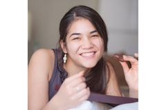 Young woman holding a piece of chocolate and smiling.