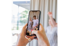 Holding a phone that is recording people on the TikTok app.
