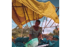 Nigerian woman selling something with plastic in foreground