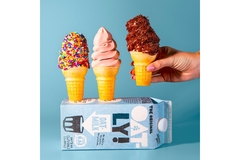 Image A tetra pak carton of Oatly drink and a hand holding an ice cream cone.