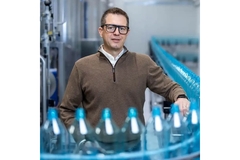 Man standing behind reusable PET water bottles.