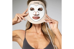 Image A woman putting a red light mask on her face.