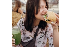 Image Girl eating burger with smoothie.