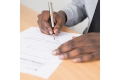 Image Two hands signing a document.
