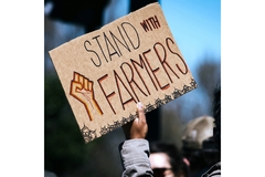 A person is holding a sign to support farmers.