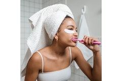 Image A woman brushing her teeth with her hair in a towel.