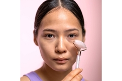 Image A woman using a jade face roller.